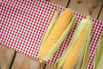 Fresh corn on cobs on rustic wooden table, closeup