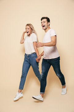Young loving couple walking isolated over beige wall background.