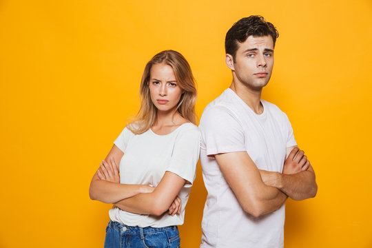 Young loving couple standing isolated over yellow wall background quarrel.