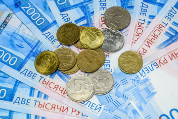 Russian banknotes and coins. A handful of coins on new Russian banknotes in denominations of 2000 and 200 rubles