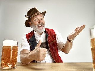 Germany, Bavaria, Upper Bavaria. The senior happy smiling man with beer dressed in traditional...