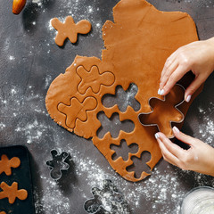 Top view christmas food concept Woman cooking gingerbread man cookies Christmas dark background flat lay Xmas dessert
