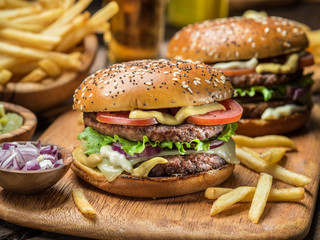 Hamburgers and French fries on the wooden tray.