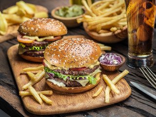 Hamburgers and French fries on the wooden tray.