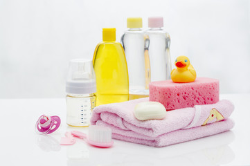 Still life with babt hygiene and bath items, shampoo bottle, essential oil, baby soap, towel, pacifier, rubber toy, shower puff