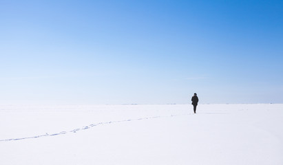 Lonely girl walks along the endless snowfield