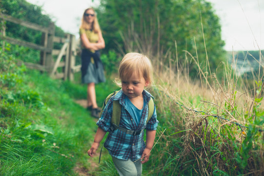 Little toddler walking in countryside with mother
