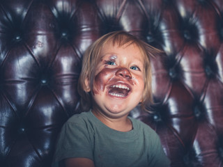 Laughing toddler with lipstick on face