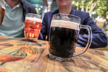 Two mugs of dark and light beer on vintage tavern table. Concept of a friendly feast, a fun meeting.
