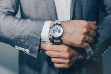 Businessman luxury style. Men style.closeup fashion image of luxury watch on wrist of man.body detail of a business man.Man's hand in a grey shirt with cufflinks in a pants pocket closeup. Toned - obrazy, fototapety, plakaty