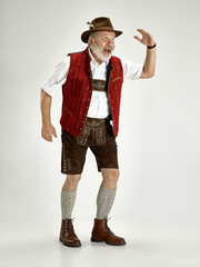 Portrait of Oktoberfest senior man in hat, wearing a traditional Bavarian clothes standing at full-length at studio. The celebration, oktoberfest, festival concept