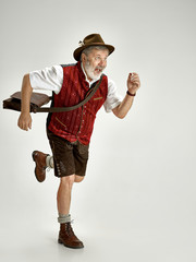 Portrait of Oktoberfest senior man in hat, wearing a traditional Bavarian clothes going at...