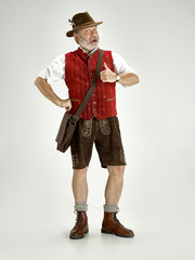 Portrait of Oktoberfest senior man in hat, wearing a traditional Bavarian clothes standing at...