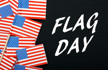 The words Flag Day on a blackboard next to miniature flags of the United States of America