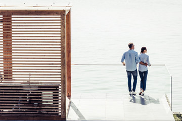 high angle view of stylish couple standing on pier near lake at country house