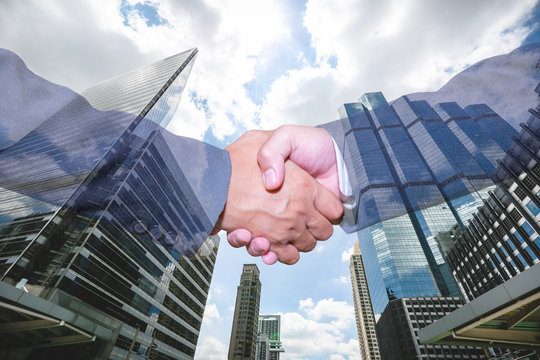 Double exposure of handshake and city.handshake and business people concepts. Two men shaking hands isolated on cityscape background. Close-up image of handshake between two business man.