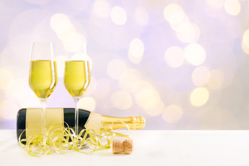 Liegende Champagner Flasche mit gefüllten Gläsern vor einem goldenen bokeh Hintergrund