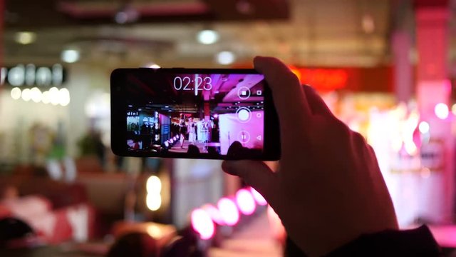 Spectators hands holding shooting video via smartphone of a concert performance