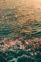 water surface with drops and splashes in the sunset and turquoise water  