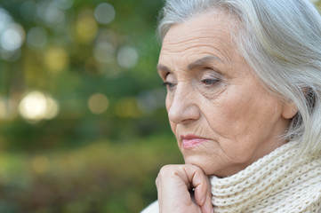 Portrait of sad senior woman in autumn park