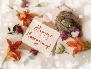 housewarming card/wooden bird in the nest, and a lilies  on the white wooden background / birthday,mother day, summer holidays concept