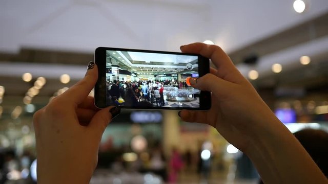 Hands holding shooting video via smartphone of a festival event