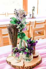Purple lavender wedding. Table decor with dry lavender, green and white flowers. Candles, wooden rustic vases, Glass jars, lace bottles, sawed wood.