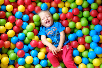 Laughing child in a game pool with colorful balls