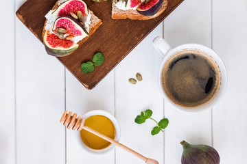 Coffee and delecious ricotta toast with figs on the white table
