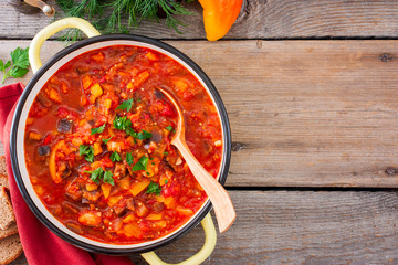 Moldovan vegetable gyuvech (eggplants, peppers, tomatoes, onions, carrots, fresh greens) in round form, top view, horizontal, copy space