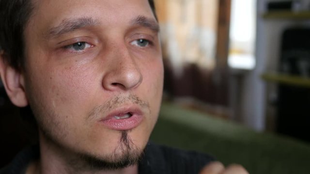 Man smokes electronic cigarette at home exhaling smoke face closeup
