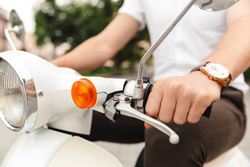 Cropped image of Young business man riding on retro scooter