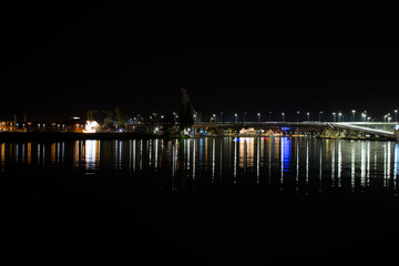 Fototapeta na wymiar night lights of buildings and bridge reflection on river water 