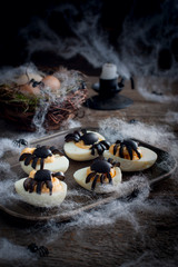 Stuffed eggs for Halloween adorned with spiders from olives, selective focus
