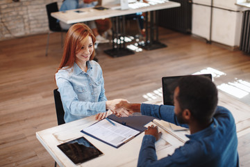 Young woman signing contracts and handshake with a manager