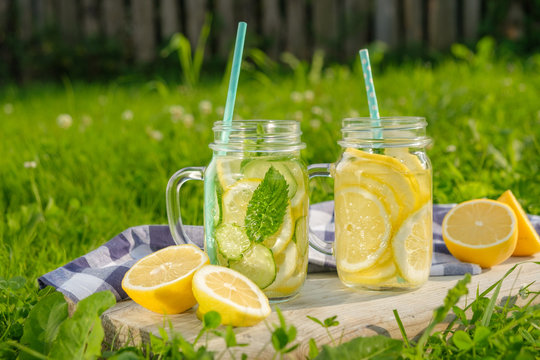 Lemonade in jars of hipster for jam on a background of green grass. Concept: picnic with refreshing drinks
