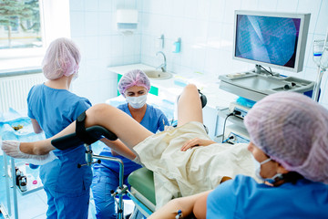 Woman gynecologist, anesthetist and female assistant with hysteroscopy equipment carry out...