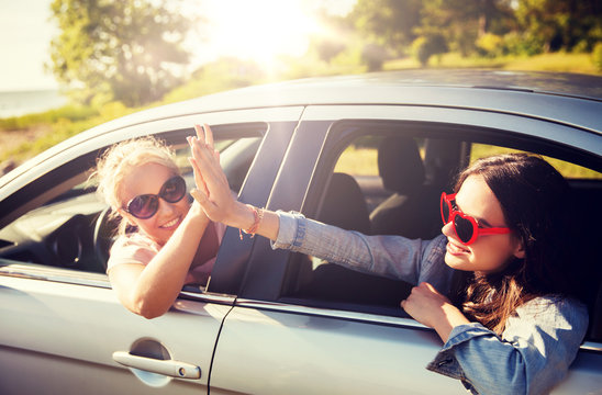 Summer Vacation, Holidays, Travel, Road Trip And People Concept - Happy Teenage Girls Or Young Women In Car At Seaside Making High Five Gesture