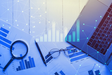 Magnifying glass and documents with analytics data lying on table,selective focus