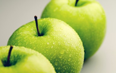 Row of green apples on green background
