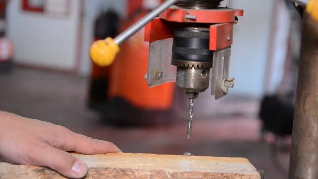 Craftsman drilling piece of wood with drill in workshop