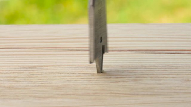 Closeup of a wood spade bit with number 16 is drilling a hole in a wooden plank. Outdoors. Copy space.