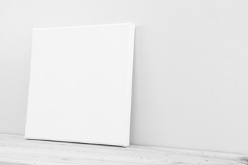 Mock-up poster frame in neutral gray interior.  White canvas, side view.