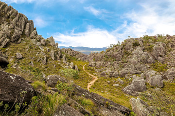 Fototapeta na wymiar trail in the mountain between rocks with blue sky and clouds, Pico das Almas, Rio de Contas, Bahia, Brazil
