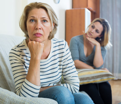 Upset young woman and senior mother having bad argue indoor