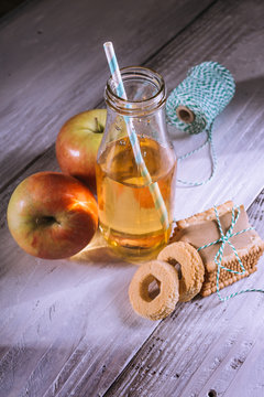 apple juice in bottle and biscuits on white wooden table
