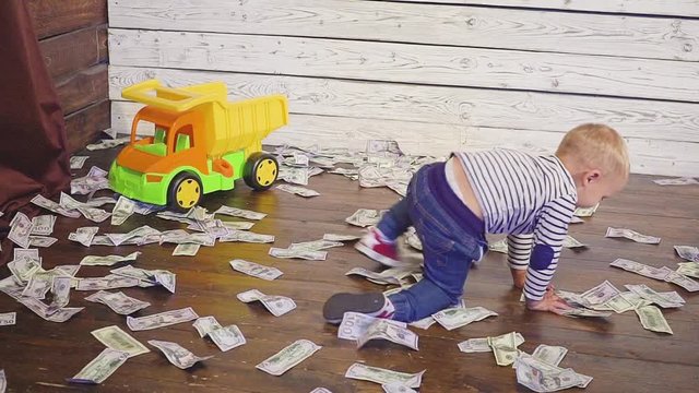 The boy is played with a toy car on the floor, where a lot of money. concept of wealth