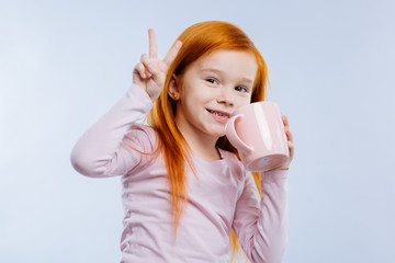 Delicious drink. Happy nice girl holding a cup while enjoying her tea