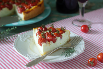 Tart, pie or cheesecake with cottage cheese and tomatoes, served with red wine on a wooden background.