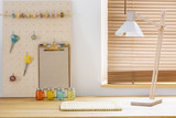 Lamp on wooden desk in workspace interior with scissors and handmade bracelet. Real photo